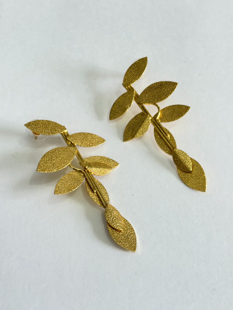 Parna gold-plated leaf earrings styled with an elegant outfit
